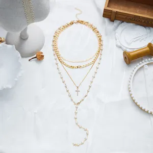 Vue détaillée d'un collier multicouche doré en forme de Y avec croix et perles