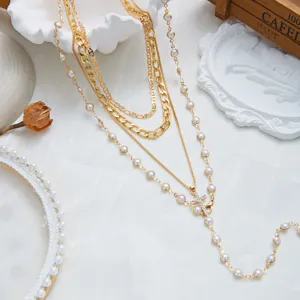 Vue détaillée d'un collier en Y multicouche doré orné d'une croix, perles et strass