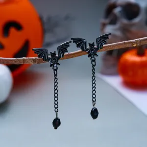 Dettaglio di orecchini vintage a pipistrello nero con catena e pendente a goccia per Halloween.