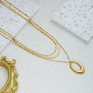 Close-up of minimalist triple-layered gold snake chain necklace with oval pendant