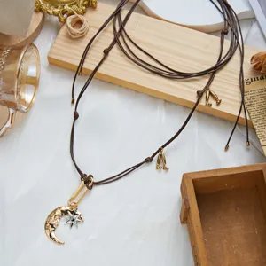 Detailed shot of vintage gold moon and star pendant on brown Bohemian cord necklace