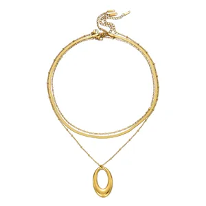 Detailed view of a gold triple-layered necklace with a smooth hollow oval pendant
