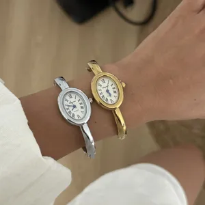 Detailaufnahme eleganter ovaler Armreifuhren in Gold und Silber mit römischen Ziffern.