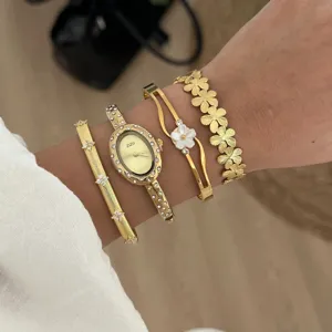 Elegante orologio ovale dorato abbinato a vari braccialetti a fiori in dettaglio