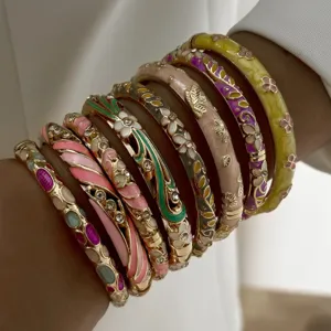Close-up of stacked macaron pastel enamel floral bangles with gold-tone alloy