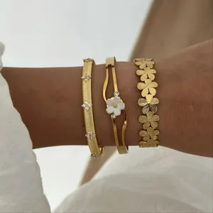 Primo piano di set di braccialetti a fiori dorati con accenti in cristallo e conchiglia