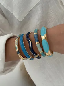 Détail rapproché de bracelets rétro en émail avec contraste de bleu et accents dorés.