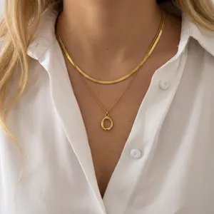 Layered gold snake chain and geometric pendant necklace set shown on a female model