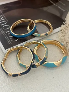 Gros plan de bracelets vintage en émail avec couleurs contrastées et finition dorée