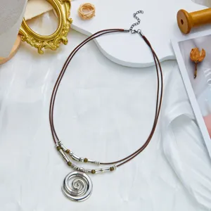 Detail view of a bohemian necklace with an antique silver spiral pendant and brown cord