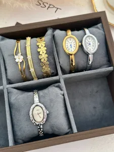 Primo piano di eleganti orologi ovali argento e set di bracciali floreali dorati in velluto