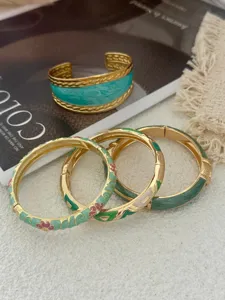 Gros plan de bracelets vintage en émail aux motifs floraux de style impérial.