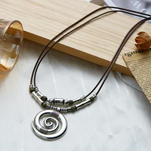 Detailed view of bohemian style spiral silver pendant on brown cord necklace