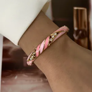 Close-up of macaron pink enamel bangle featuring sparkling rhinestones on a gold alloy band