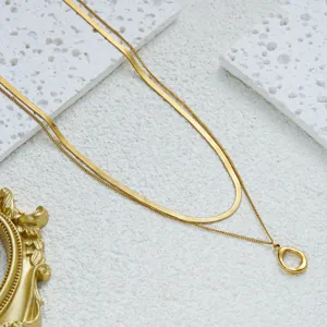 Detail of minimalist gold double-layer necklace with snake chain and oval hollow pendant