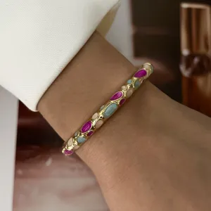 Close-up detail of a macaron pastel enamel slim gold-tone bangle worn on a female wrist