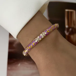Macro detail of an elegant purple macaron enamel bangle featuring floral patterns on wrist.