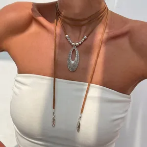 Close-up of bohemian western style silver hollow pendant on brown suede cord necklace