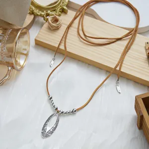 Detailed view of a bohemian style antique silver hollow oval pendant with brown suede cord