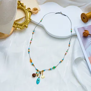 Detailed view of a bohemian beaded necklace with turquoise pendant on a white platform