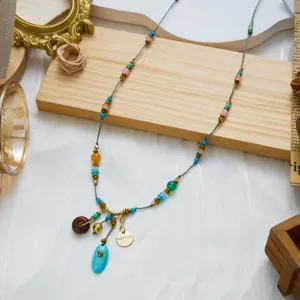 Close-up of bohemian beaded necklace with colorful stones and vintage gold charms decoration.