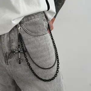 Nahaufnahme einer dunklen gotischen schwarzen doppelten Hosenkette mit Kreuzanhänger auf Jeans