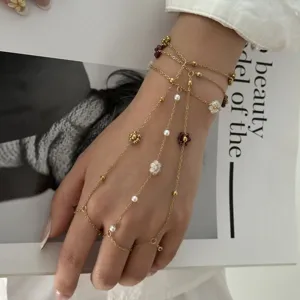 Dettaglio ravvicinato del bracciale a catena multistrato dorato con perle floreali.
