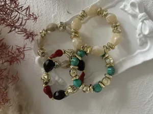 Detailansicht der Vintage-Acryl-Armbänder mit marmorierten und goldenen geometrischen Perlen.
