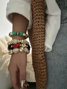 Nahaufnahme von retro-unregelmäßigen Acryl- und goldenen CCB-Perlenarmbändern am Arm.