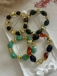Detailansicht von vintage marmorierten Acryl- und Goldperlenarmbändern auf Tablett.
