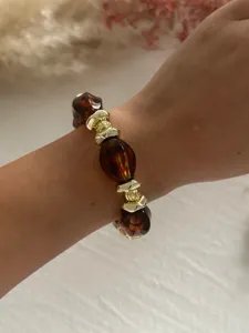 Nahaufnahme eines Retro-Acrylarmbands mit Schildpatt- und goldfarbenen Metallperlen am Handgelenk