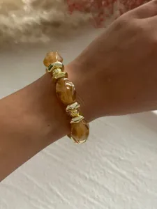 Nahaufnahme eines marmorierten Bernstein-Acrylarmbands mit goldenen CCB-Perlen am Handgelenk