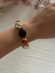 Nahaufnahme eines Vintage-Armbands mit marmorierten Acryl- und goldenen CCB-Perlen am Handgelenk.