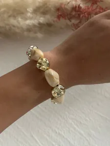 Nahaufnahme eines Retro-Armbands aus Acrylmarmor und goldfarbenen Perlen am Handgelenk