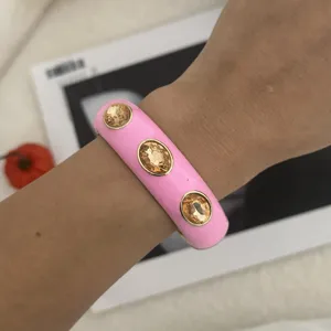Detailansicht eines rosa Emaille-Armreifs mit drei ovalen bernsteinfarbenen Kristallen