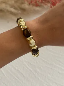 Nahaufnahme eines Vintage-Armbands mit goldenen Perlen und braunem Acryl-Detail.