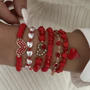 Detailed view of Valentine's Day stacked red beaded bracelets with heart charms