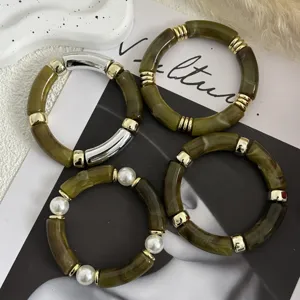 Dettaglio di bracciali in acrilico verde oliva con accenti dorati e perle eleganti.