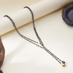 Detailed macro view of a layered black beaded necklace with a golden heart pendant piece.
