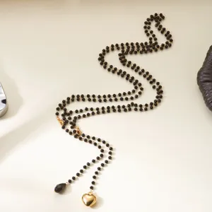 Detailed macro view of a layered black bead necklace with a gold heart pendant