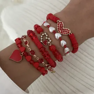 Close-up detail of romantic red heart pendant layered bracelet set worn on wrist