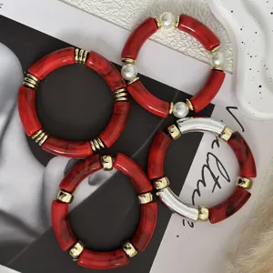 Dettaglio ravvicinato di bracciali in tubo acrilico marmorizzato rosso con perle.