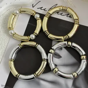 Primo piano di eleganti bracciali a tubo in acrilico con finiture oro, argento e perle