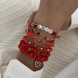 Detailed view of a red heart stacked bracelet set with white LOVE beads on wrist