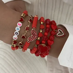 Detailed macro view of red heart charm and LOVE letter beads on a stacked bracelet set
