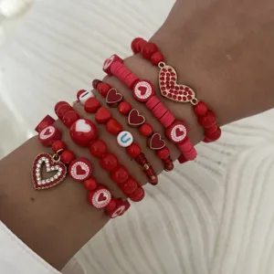 Close-up of stacked Valentine's Day red beaded bracelets with gold heart charms