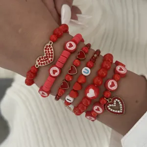 Detailed view of red beaded stacked bracelets with crystal heart pendants on wrist
