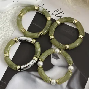 Dettaglio di bracciali in acrilico effetto marmo verde con inserti oro e argento.