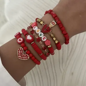 Close-up of red and gold stacked bracelet set with heart charms and LOVE beads decor