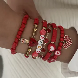 Macro view of red heart pendant and LOVE alphabet beads on stacked bracelets.